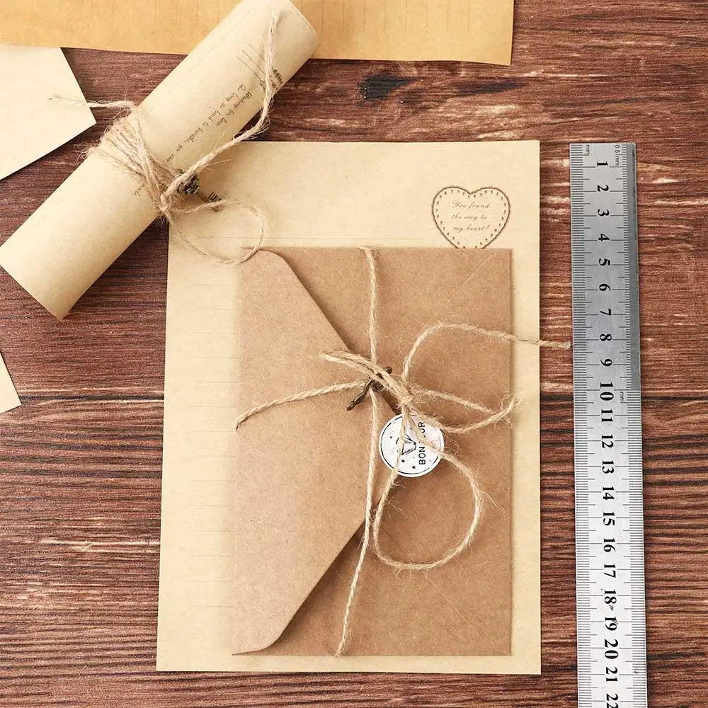 A set of vintage European style letter and invitation envelopes tied with twine on a wooden surface next to a ruler.