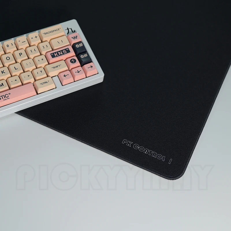 A white mechanical keyboard is placed on a black gaming mouse pad desk mat.