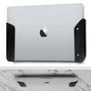 A silver laptop is shown mounted on an under-desk clamp with black silicone padding.
