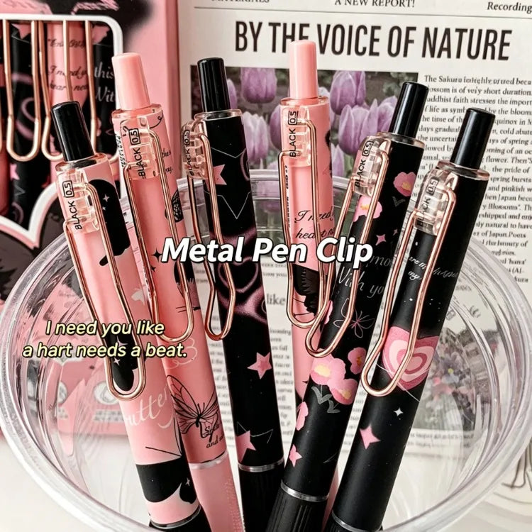A set of six metallic pink and black butterfly design gel pens displayed in a clear glass bowl.