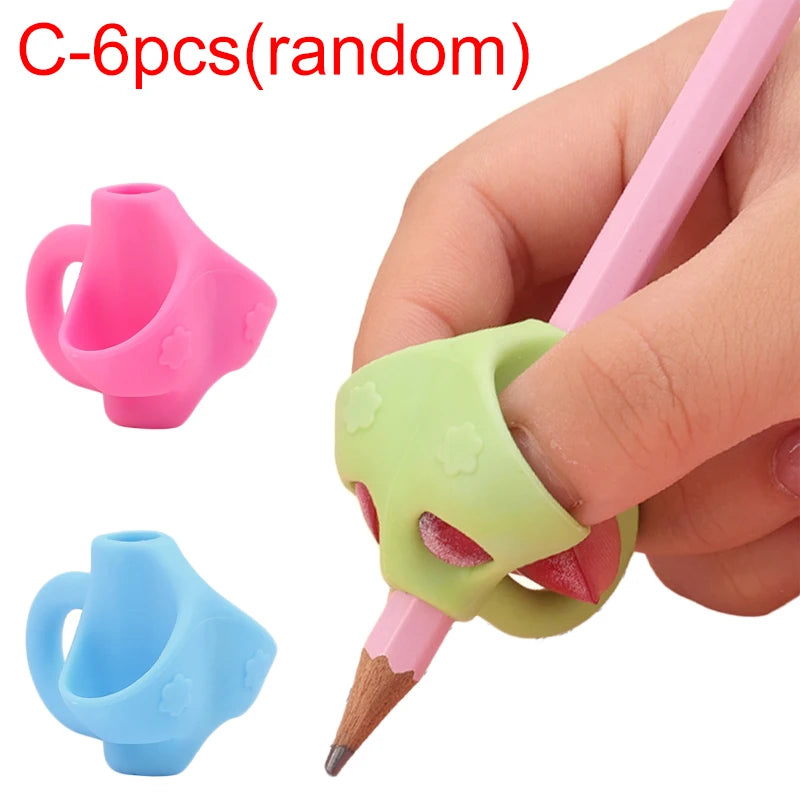 Hand holding a pink and green silicone pencil grip writing corrector for children