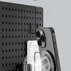A black smartphone is magnetically suction-mounted onto a dark surface, demonstrating its use as a mobile phone stand.