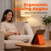 A woman is sitting comfortably and using a flexible silicone multi-angle phone and tablet stand for viewing.