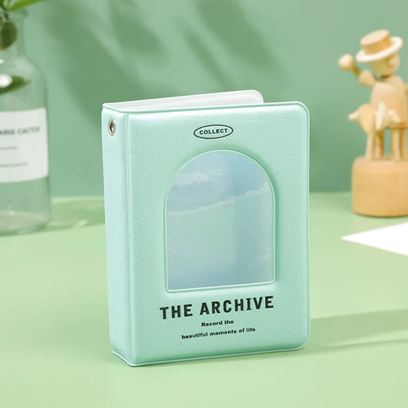 A light mint green hollow photo card binder titled The Archive with a clear arched window.