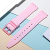 A pink silicone watch strap is shown lying on a light blue background with replacement tools.