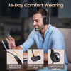 A man wearing a black Bluetooth headset for all-day comfort while working on a laptop.