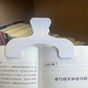 A close-up of a white book page clip with a curved shape, used to hold pages together.