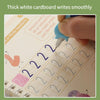 A hand writes smoothly on a white cardboard practice book with numbers and letters.