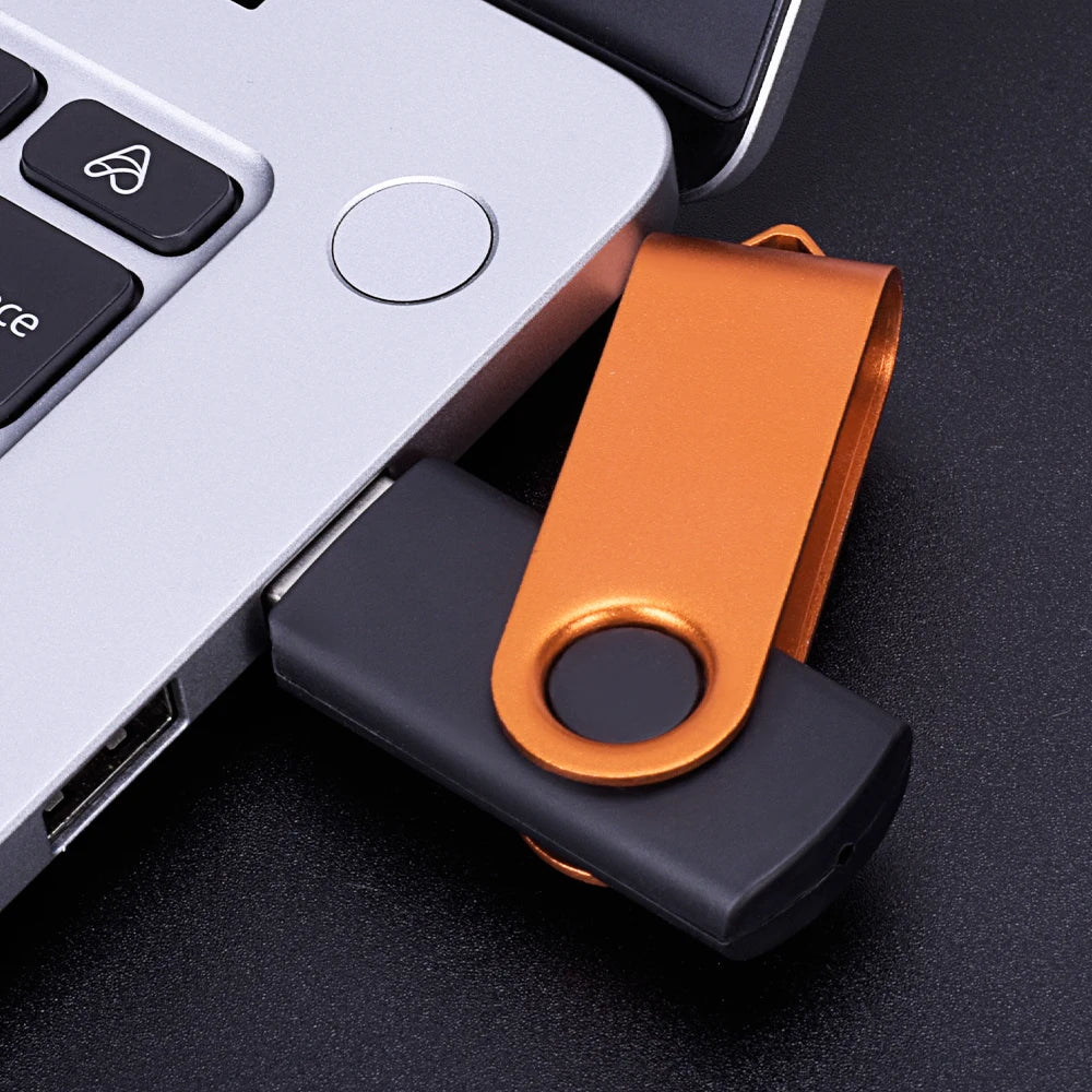 An orange metal connector for a rotatable USB flash drive resting on a dark surface.