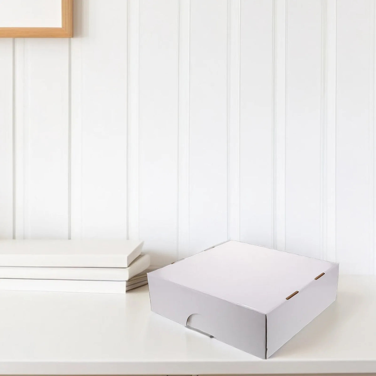Una caja rectangular blanca para guardar cartas de trading sobre una superficie blanca junto a cartas apiladas blancas.