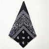 Black bandana square scarf with white paisley print featuring intricate floral and geometric patterns