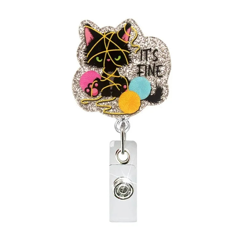 A sparkly cat-shaped badge reel with a gold-colored charm and a clear plastic clip.
