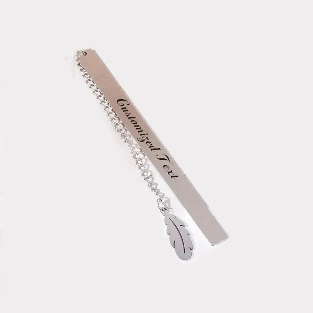 A stainless steel bookmark with engraved text hanging from a chain.