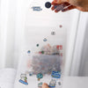 A hand holds a transparent storage book filled with various stickers and documents.