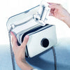 A hand is holding a white foldable phone holder stand attached to a zippered case.