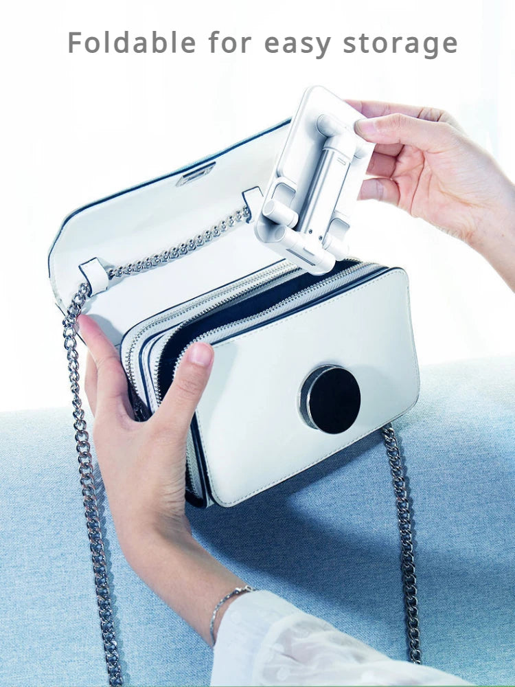 A hand is holding a white foldable phone holder stand attached to a zippered case.