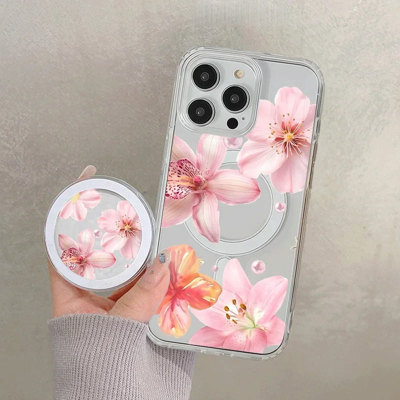 A hand holds a clear floral magnetic phone case for an iPhone featuring pink and orange flowers.