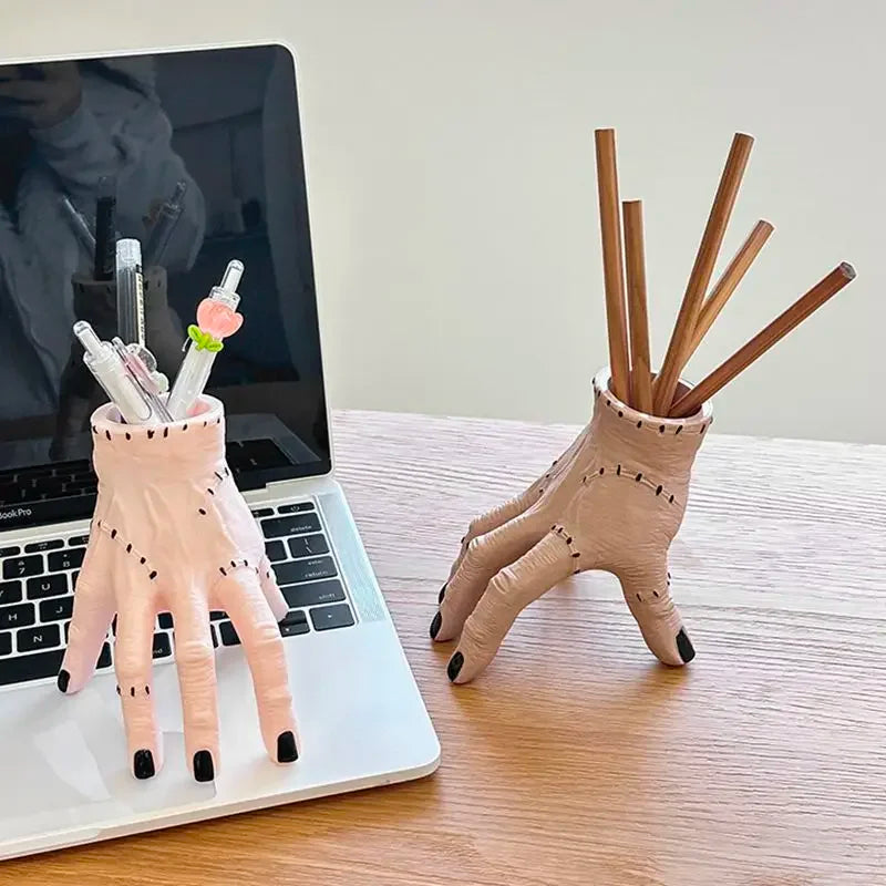 A hand-shaped decoration made of pink resin palm with wooden sticks inside, resting on a laptop.