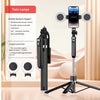A black portable Bluetooth selfie stick tripod with two round lights and a smartphone mount is displayed on a wooden surface.