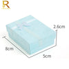 A rectangular light blue jewelry gift box with a white ribbon, shown from above and side views.