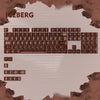 A close-up view of a mechanical keyboard featuring light brown keycaps and the word ICEBERG displayed above.