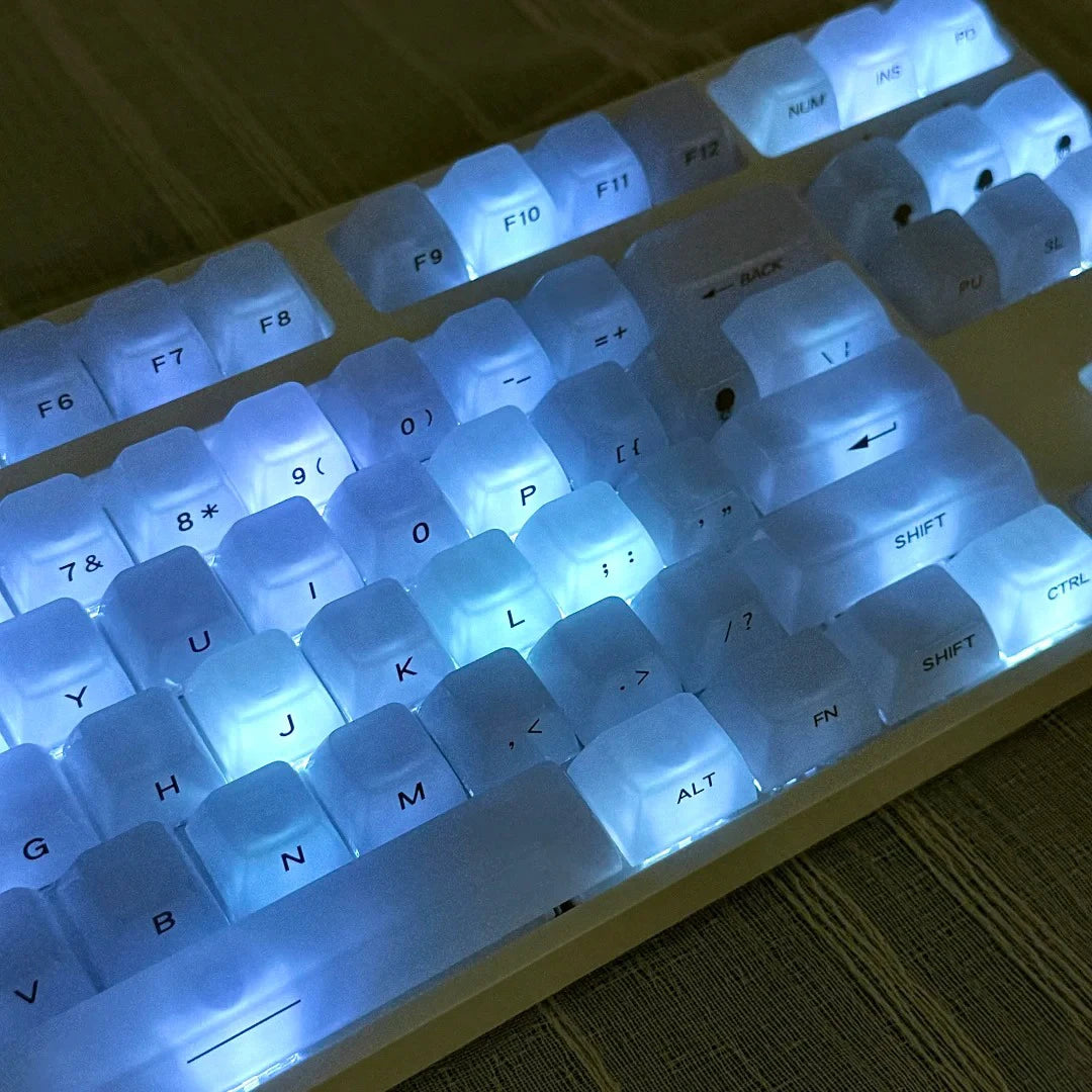 Close-up view of custom profile keycaps for a mechanical keyboard showing various letter and number keys illuminated with blu