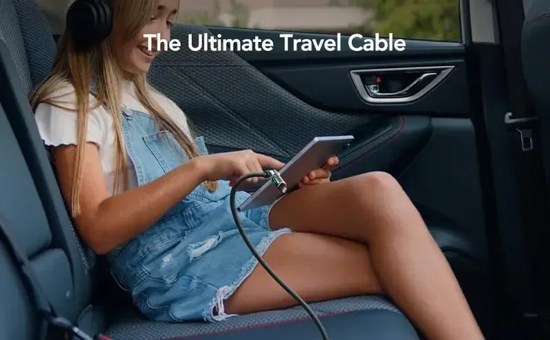 Eine junge Frau benutzt ein USB-C-Kabel, um ein Gerät im Auto zu laden oder zu synchronisieren.