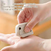 A hand is holding a white auto-retracting box cutter, demonstrating its safety feature.