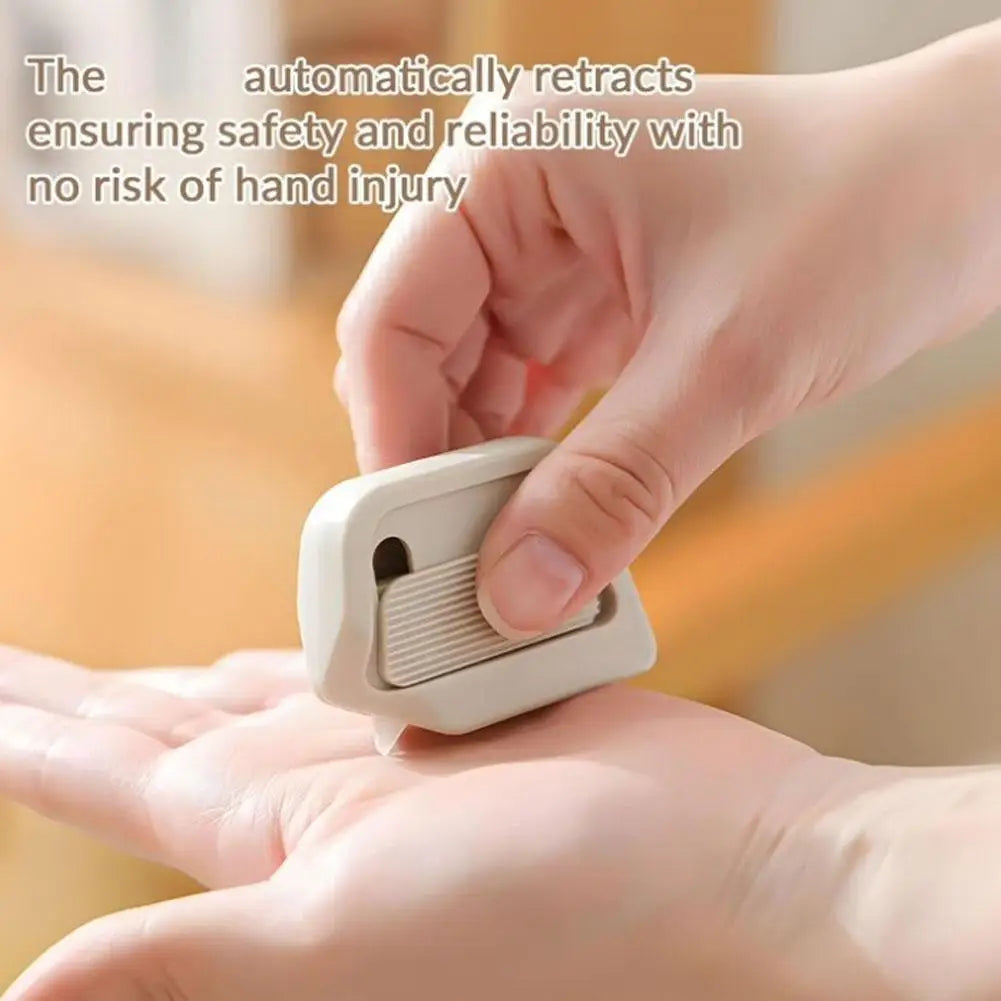 A hand is holding a white auto-retracting box cutter, demonstrating its safety feature.