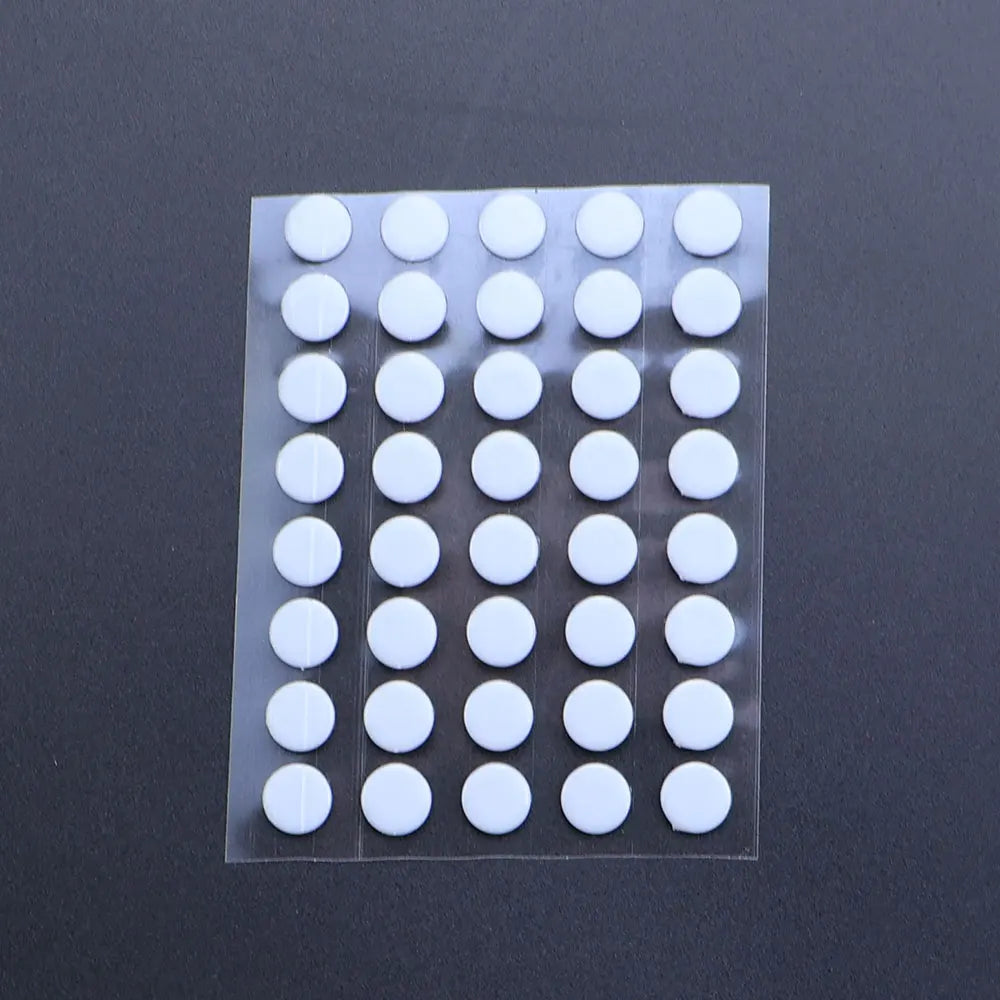 A clear plastic sheet containing 40 white adhesive glide feet for universal mouse skates.