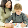 A young boy is looking at a magnetic weekly chore chart with a female adult nearby.