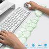 Hands place a clear, ergonomic cloud wrist rest on a white desk next to a computer keyboard.