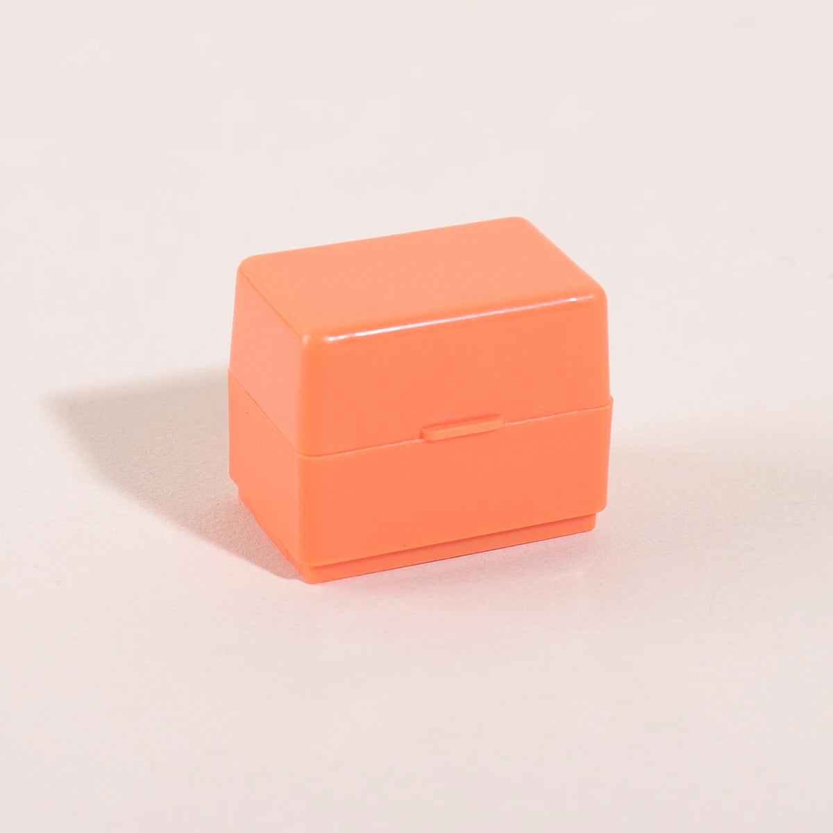 An orange privacy protection roller stamp box resting on a light surface.