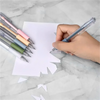 A hand is using a precision craft knife set with various colored blades to cut paper on a marble surface.