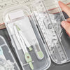 A clear plastic case holds a precision set of transparent measuring tools including pens and rulers.