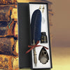 A black gift box containing a feather dip pen set with a decorative knife and a small ink bottle.