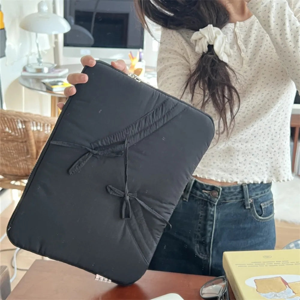 A black ultra-thin laptop sleeve case is held by a person, resting on a wooden surface.