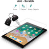 A clear anti-scratch tempered glass screen protector is shown being applied to an iPad screen, with keys, cables, and sharp o
