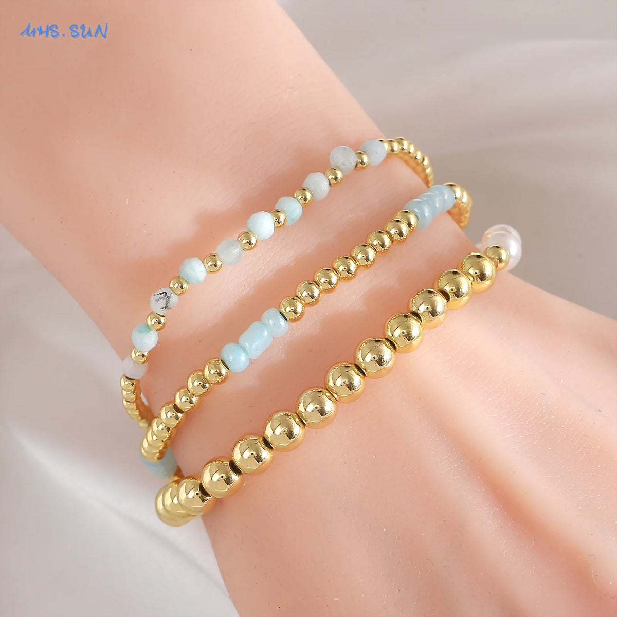 A close-up of a gold-plated shell pearl beaded bracelet worn on a wrist.