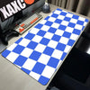 A blue and white checkered desk mat is displayed on a wooden desk next to a keyboard and a mouse.