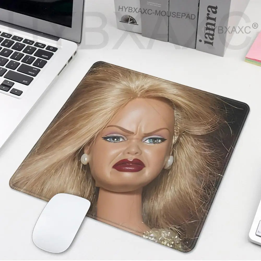 A realistic doll face is featured on a mouse pad, showing detailed makeup and blonde hair.