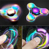 Close-up shots of a rainbow metal fidget spinner showing various colors and spinning motion.
