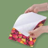 Hands are holding a sheet of high glossy self-adhesive photo paper with a vibrant pattern of fresh strawberries and citrus fr