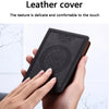 A hand holds a black leather cover notebook with an embossed design.