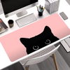 A pink mouse pad featuring a black cat face is placed on a white desk next to a computer and stationery.