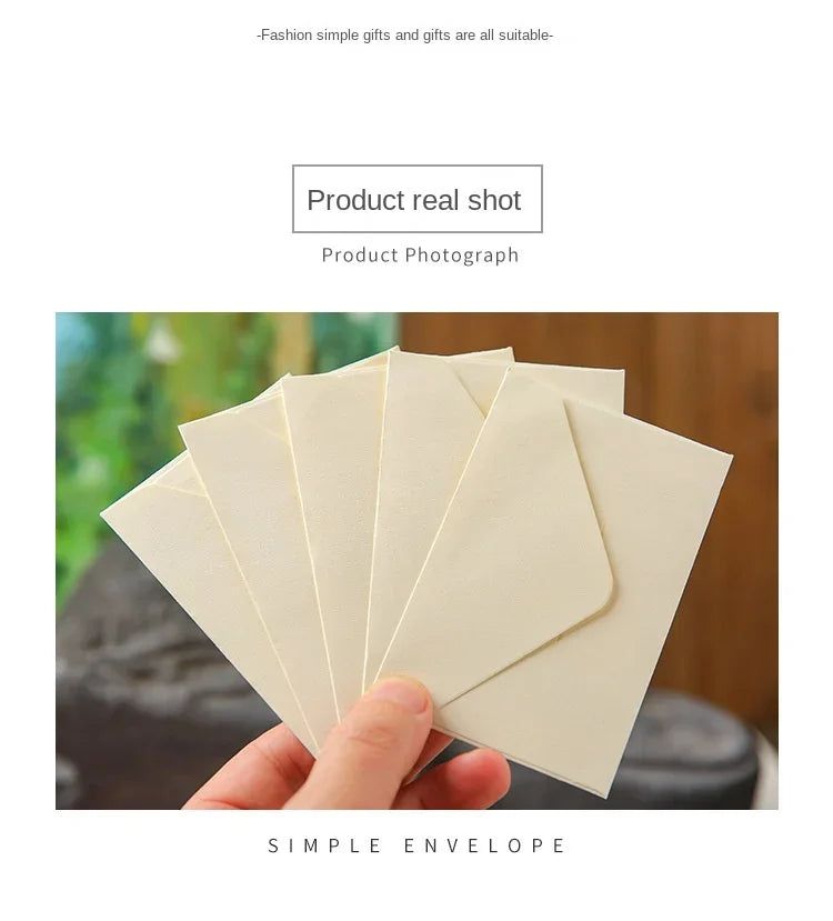 Una mano sostiene una pila de sobres de papel kraft beige claro para invitaciones de boda.