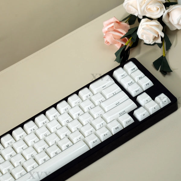 A close-up view of a black mechanical keyboard with white keycaps and a bouquet of pink and white roses.
