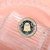 A round enamel pin featuring a white ghost with butterfly wings and text that reads Living the Dream One Nightmare at a Time