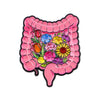 Enamel pin depicting a stylized pink stomach filled with colorful flowers and leaves.