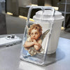 A clear phone case with a floral pattern featuring a cherub with wings is displayed next to a white tumbler.
